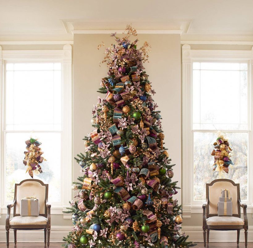 Fully decorated Christmas tree between two chairs and windows