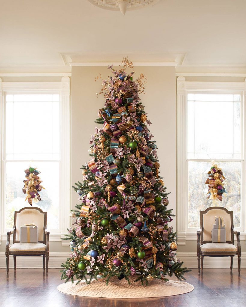 Fully decorated Christmas tree between two chairs and windows