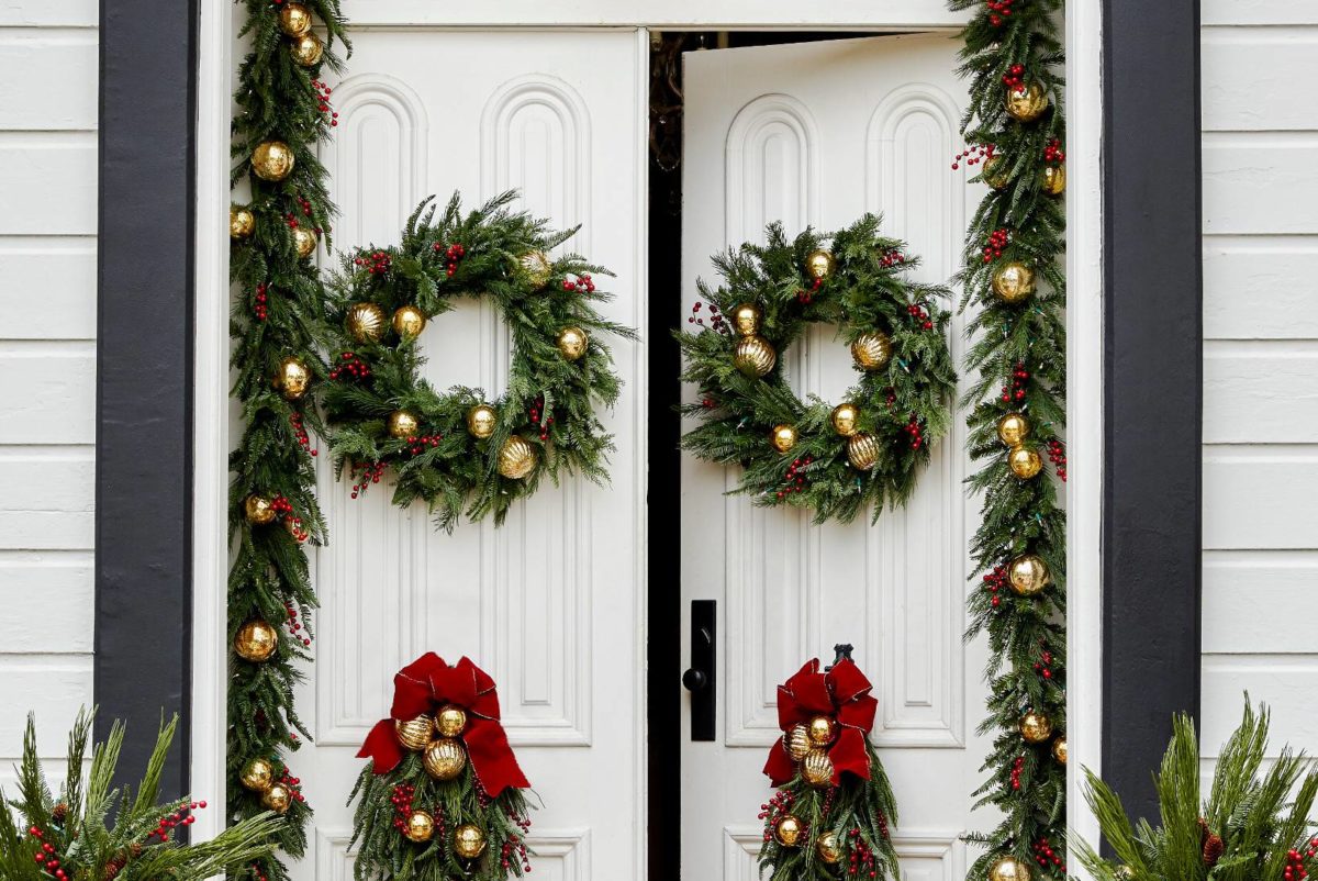 Front door decorated with greenery and gold ornaments