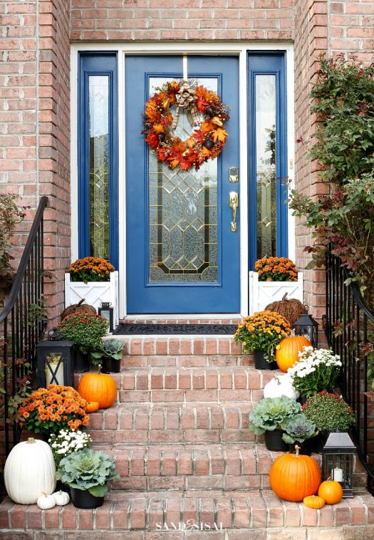 Front steps decorated with greenery and pumpkins