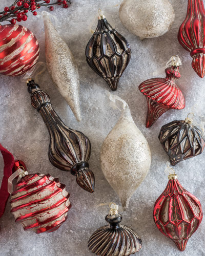 A flat lay of metallic red, gray, and white Christmas ornaments