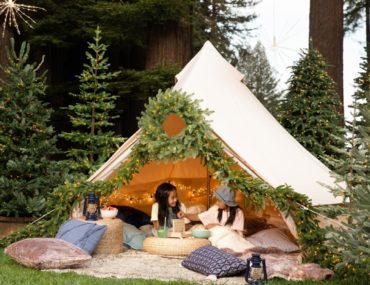 Two girls having a backyard camping with Balsam Hill artificial Christmas trees and greenery
