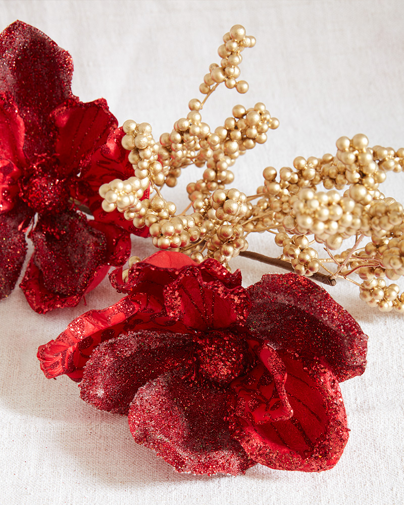 Closeup shot of tree picks with red artificial flowers and gold berries