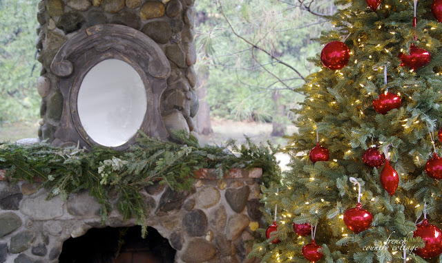 Closeup shot of a fireplace mantel with a lit-up Christmas tree on the right