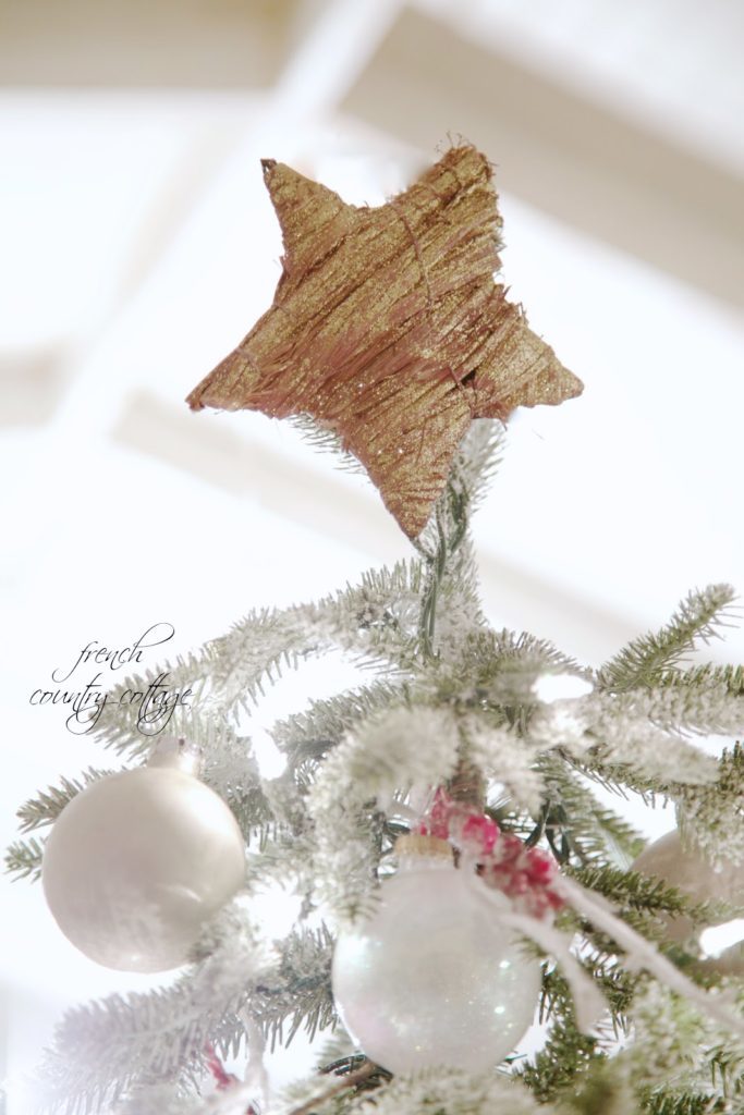 Natural jute star tree topper on top of a simple rustic cottage frosted Christmas tree