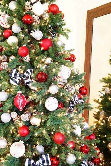 Christmas tree decorated with red, white, and black ornaments beside a mirror