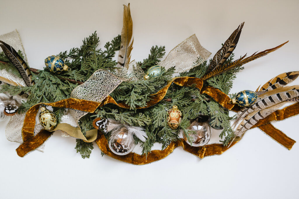 gold and velvet ribbons, feather picks, glass egg and ball ornaments, evergreen foliage
