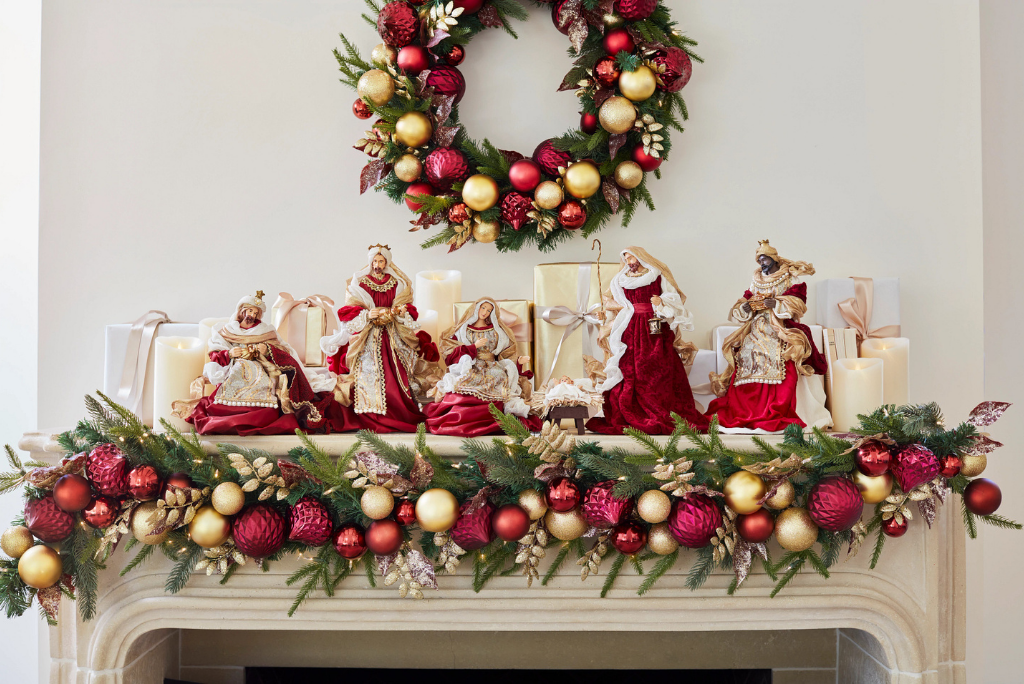 A red and gold nativity set on top of a fireplace mantel