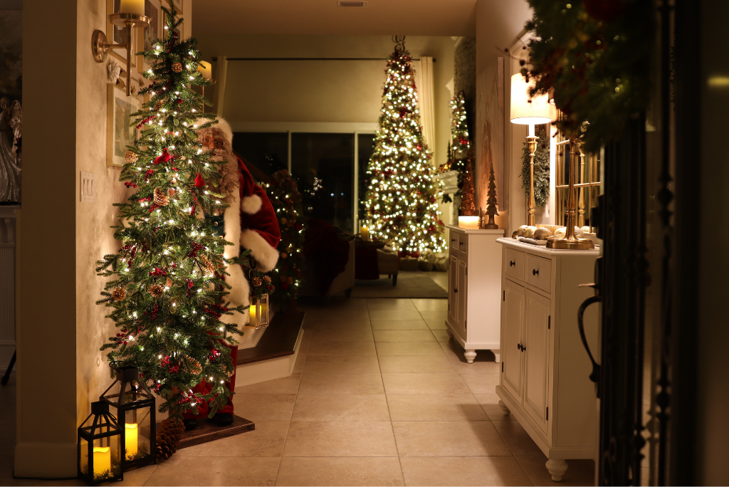 Night shot of a foyer decorated with a lit Christmas tree, life-size Santa, and LED lanterns