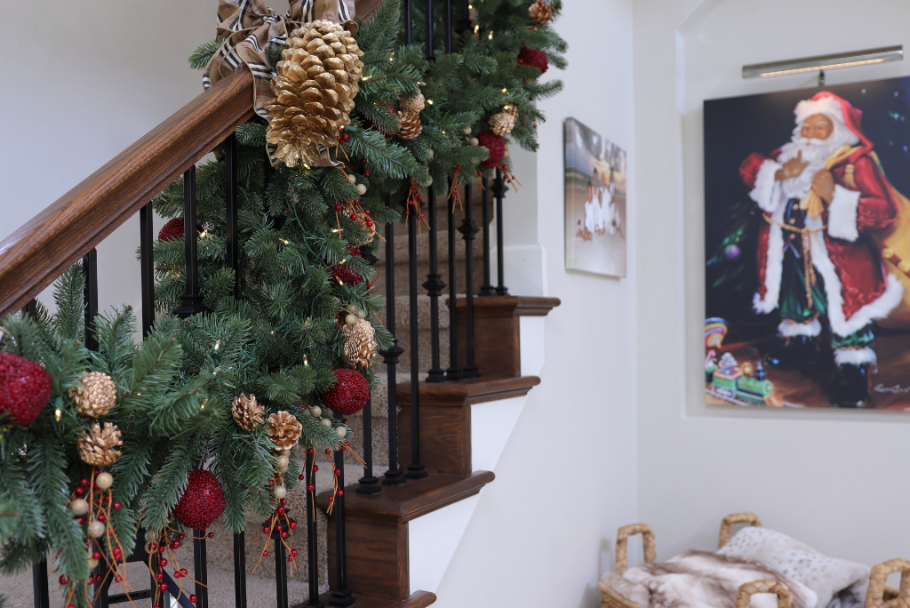 A red and gold rustic Christmas garland draped on the stair rails