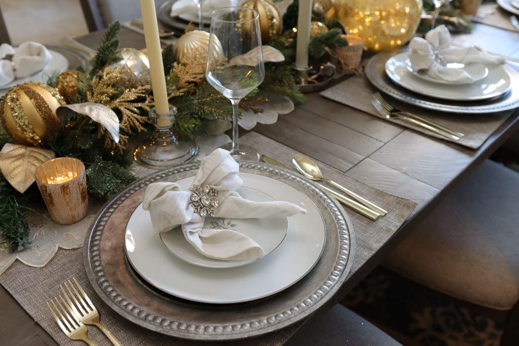 Christmas place settings featuring gold flatware, charger, salad plate, dinner plate, napkin, and napkin ring