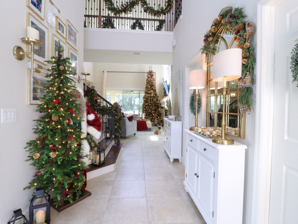 Foyer decorated with a pre-lit Christmas tree, life-size Santa, and Christmas garland