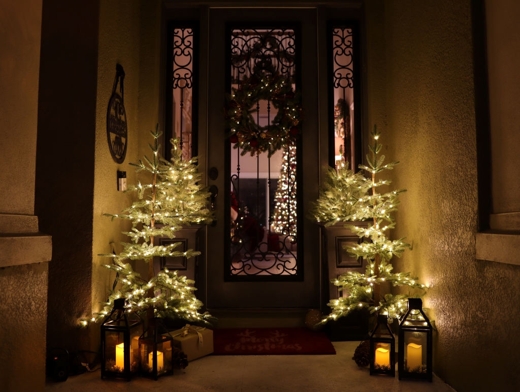 Pre-lit Christmas trees and lit lanterns as Christmas doorway decorations at night