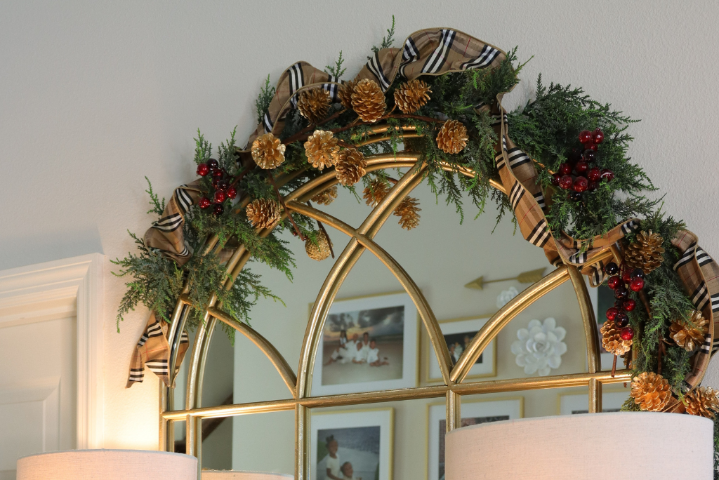 An undecorated Christmas garland decorated with berry picks, pinecone picks, and designer ribbon