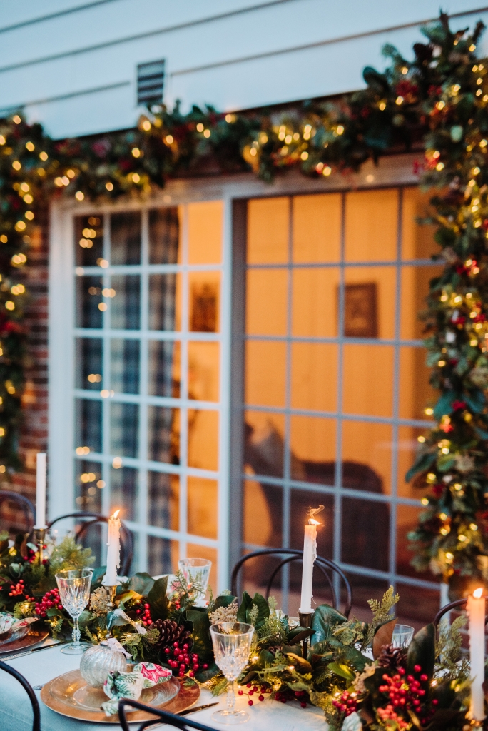 Patio with outdoor dining table decorated with pre-lit garlands