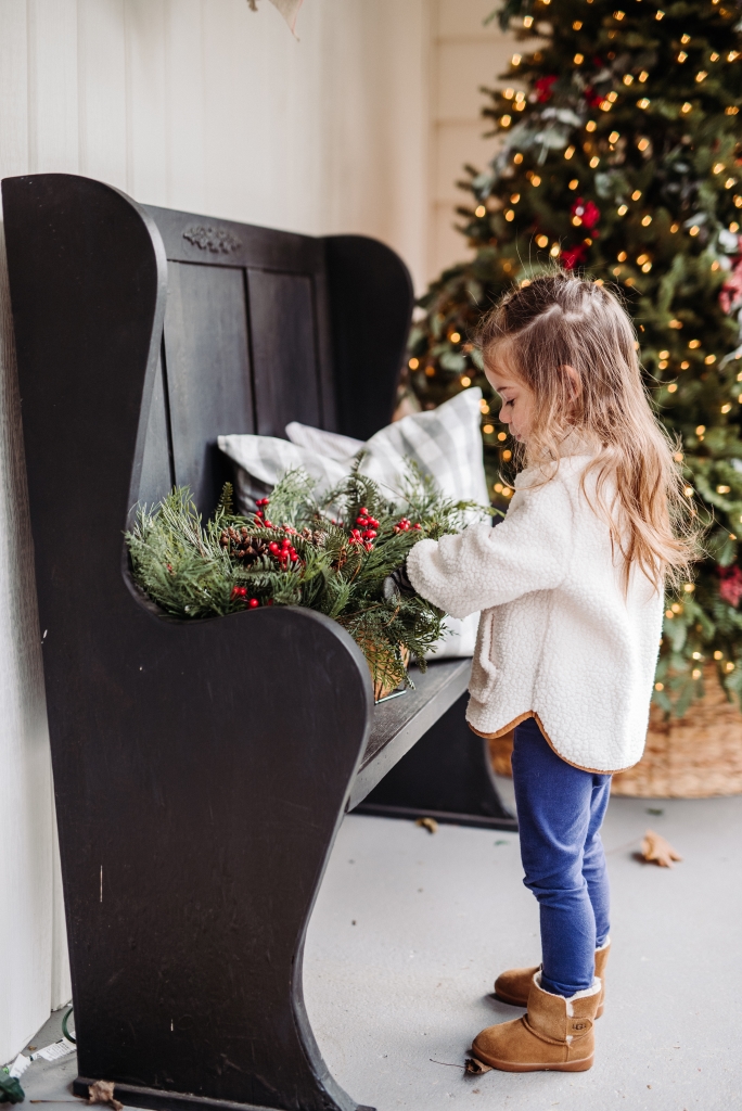 A little girl fluffing Christmas foliage window box