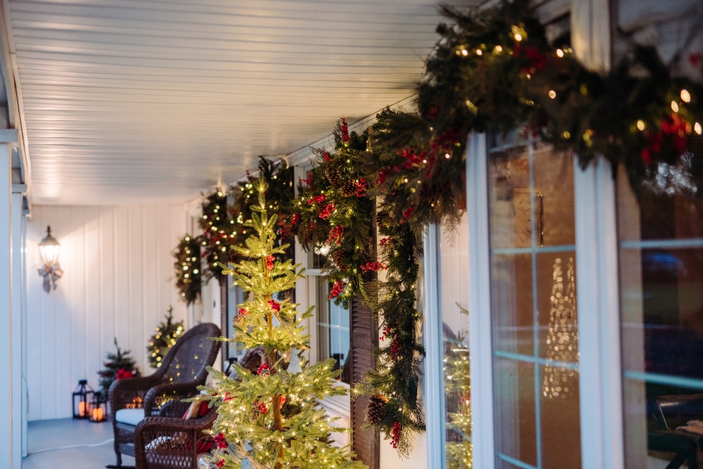 Front porch with rocking chairs, pre-lit Christmas trees, and Christmas garlands
