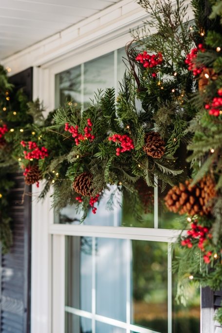 Balsam Hill Outdoor Red Berry Pine Garland hung on a porch window