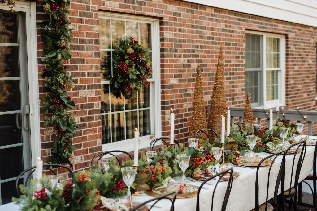 An outdoor tablescape decorated with Christmas garlands and candles