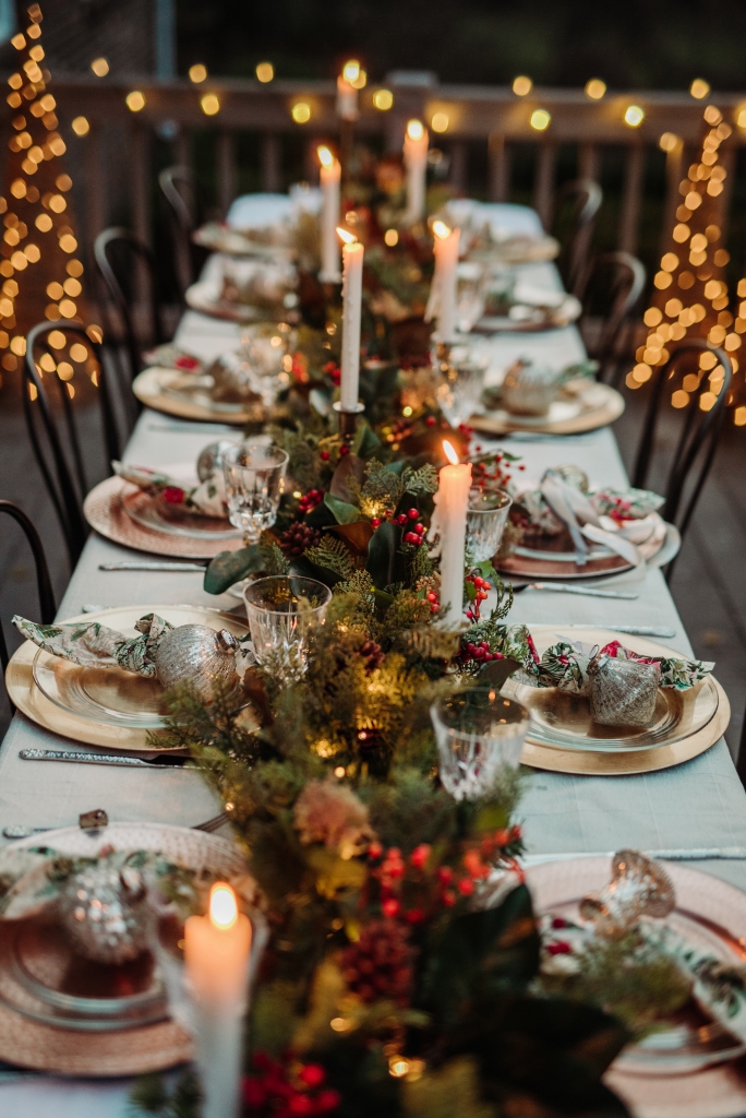 Outdoor dining tablescape with a decorated garland and candles as centerpiece