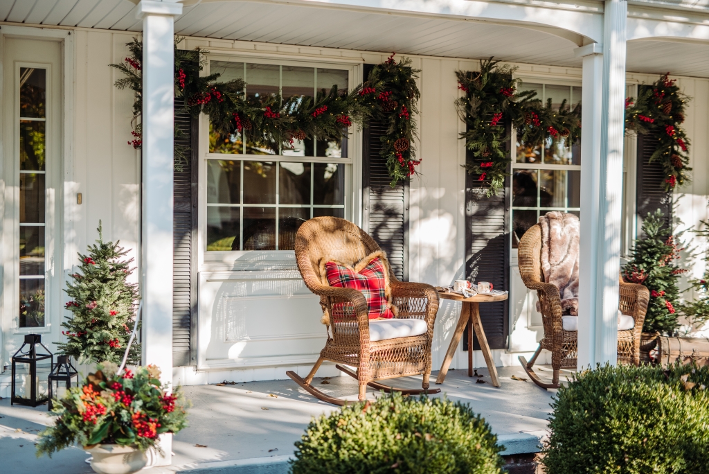 A porch decorated with rocking chairs and Christmas garlands