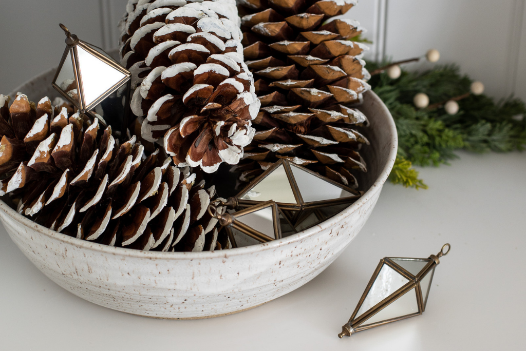 Geometric glass ornaments with pinecones set in a bowl as repurposed Christmas decorations for the winter season