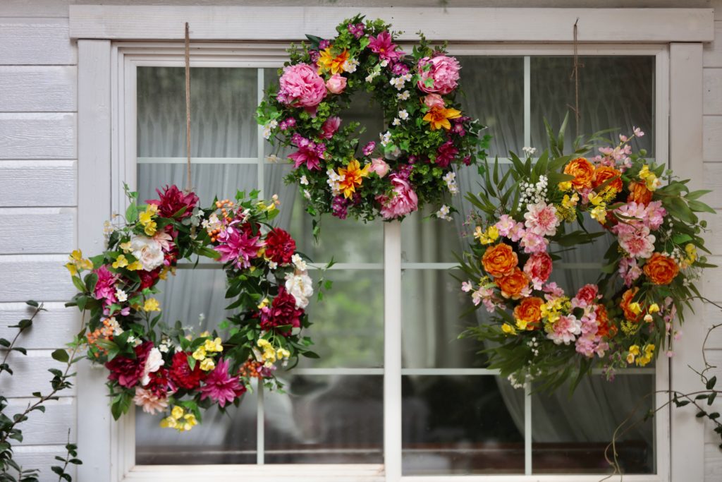 A gallery of floral wreaths hung outside a window