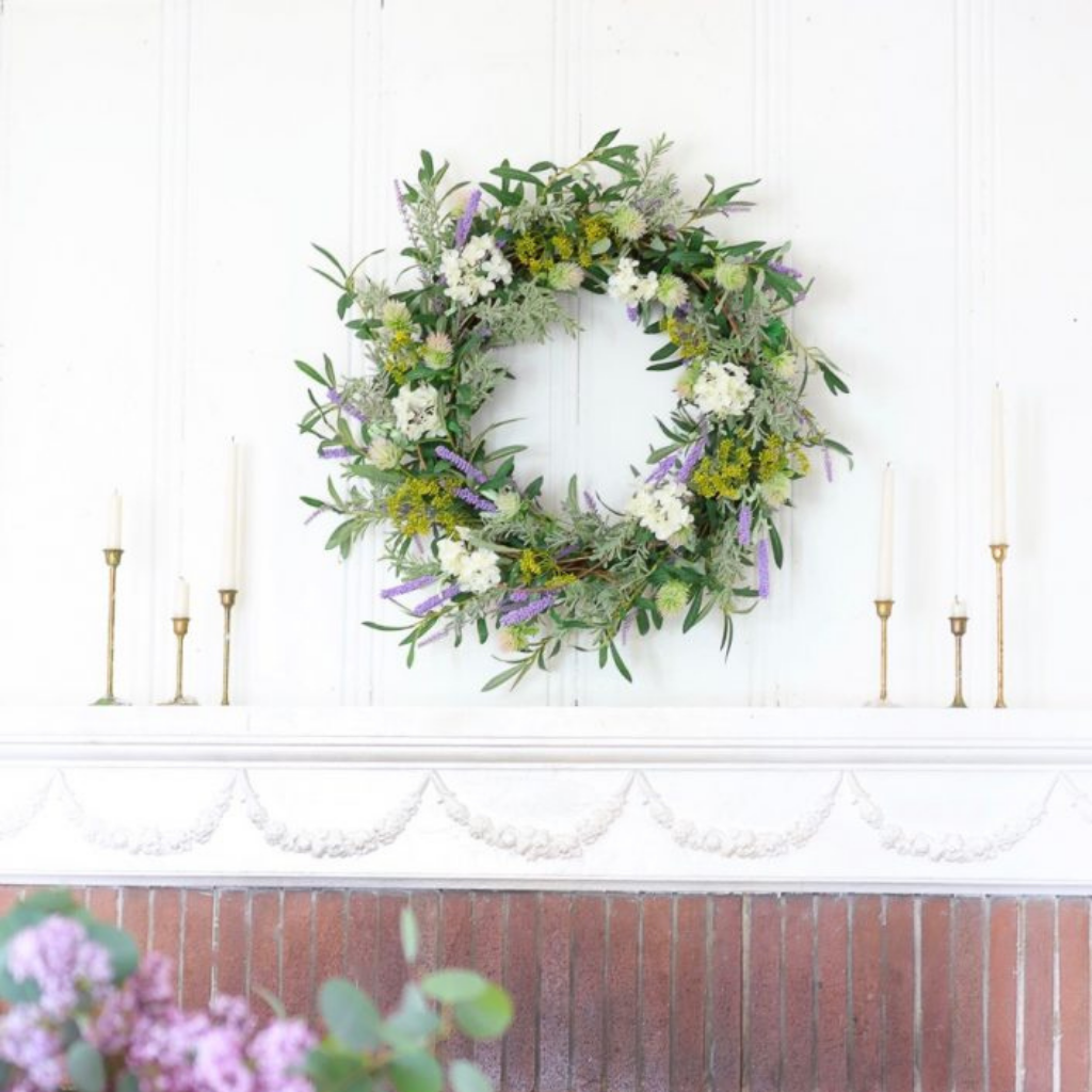 Floral wreath and taper candles on top of a mantel
