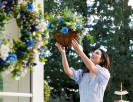 A woman setting up an artificial hanging basket outdoors