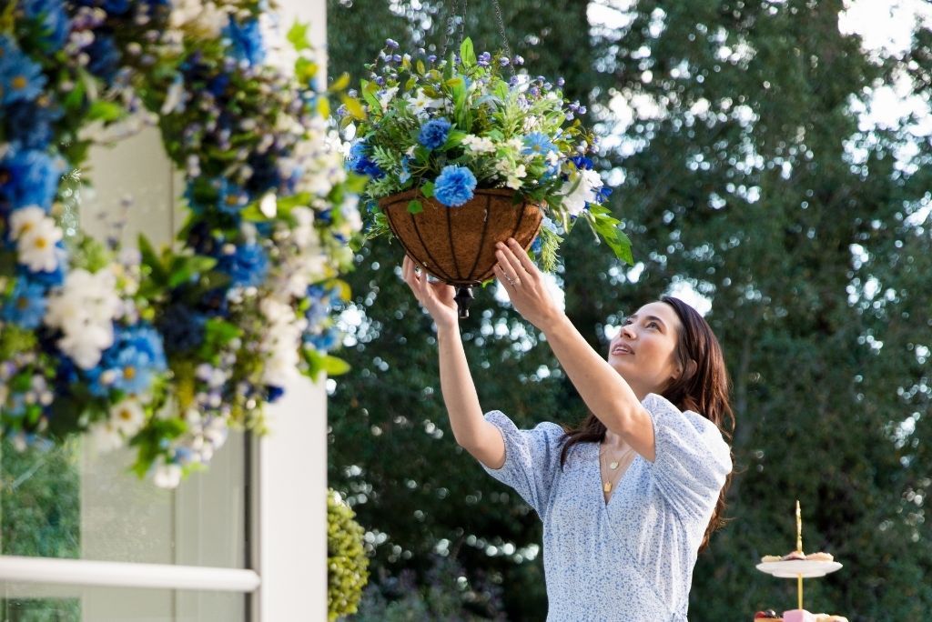 A woman setting up an artificial hanging basket outdoors
