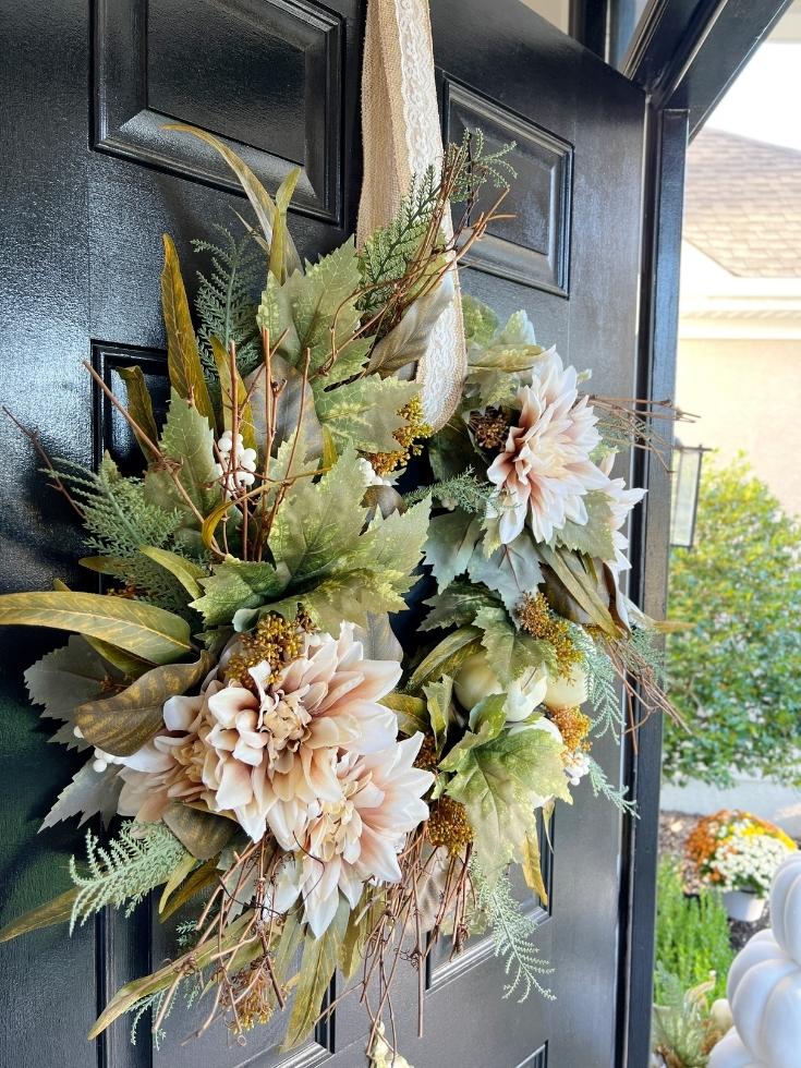 A fall wreath in a light color palette of peach, white, and muted green