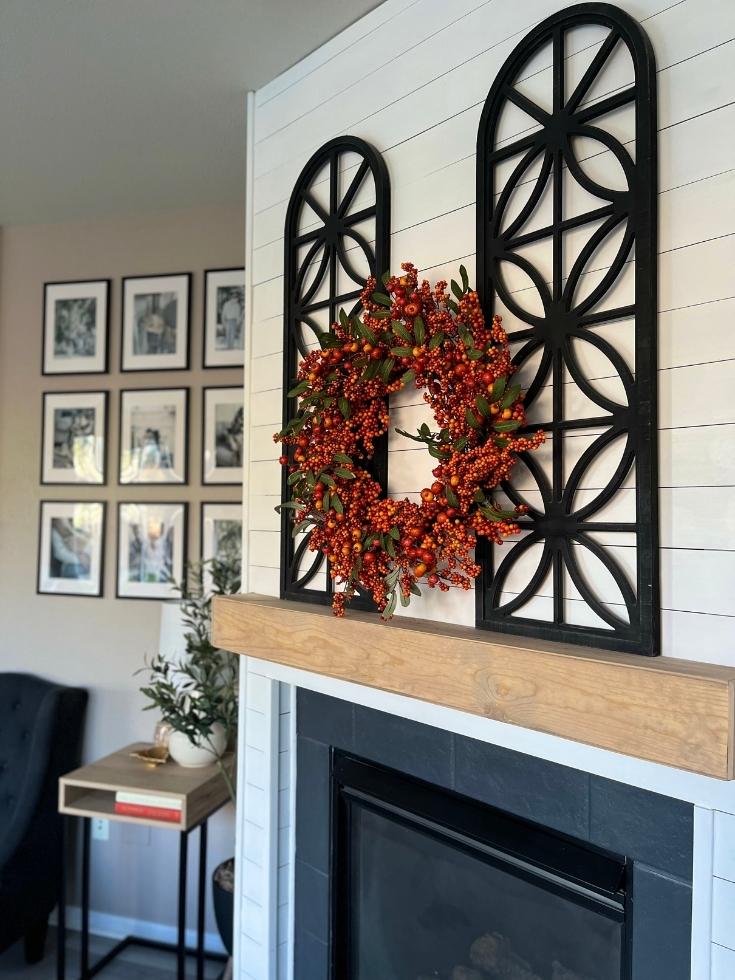 An orange berry wreath as room fall decor on the fireplace mantel